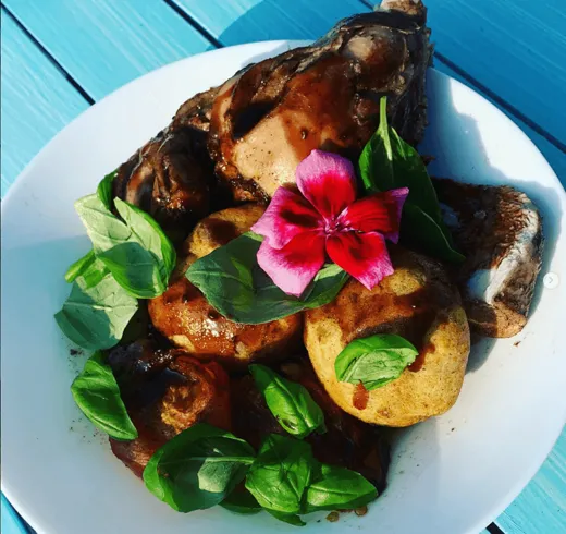 Roast chicken on roast potatoes, finished with basil and a flower