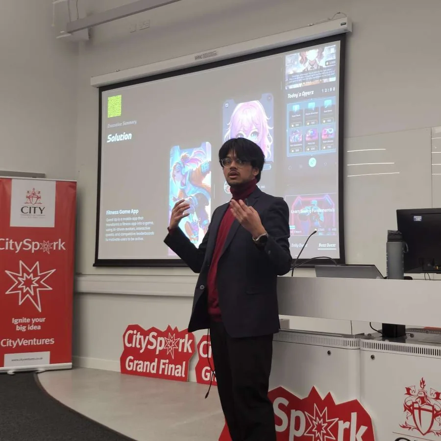 Mahin pitching Quest Up at the CitySpark Grand Final, in front of the slide showing the app&rsquo;s solution